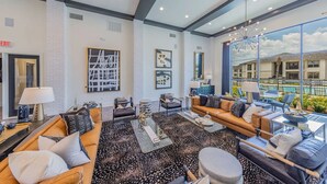 A spacious lobby with a large window overlooking a pool, a coffee table, sofas, and chairs arranged for guests. - Landing | Chic 2BD in Medical Center (San Antonio)