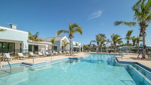 A swimming pool with lounge chairs, palm trees, and a building with a white facade. - Landing | Incredible 2BD, Yoga Studio, Gym (Bonita Springs)