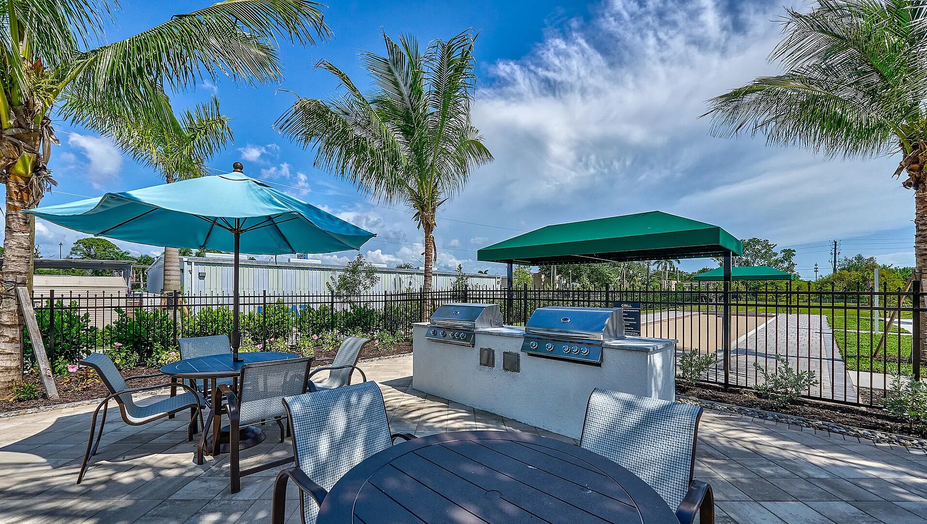 An outdoor patio with a grill, seating area, and umbrellas.