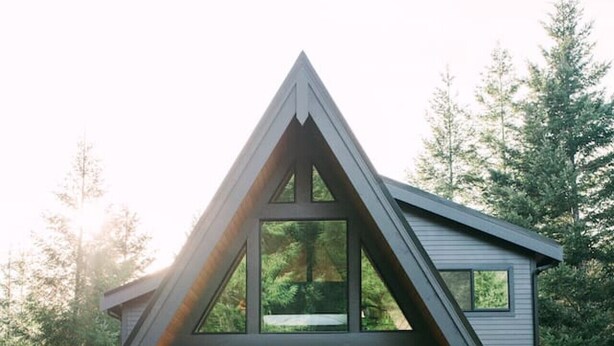 A modern, triangular wooden cabin with a central door, windows, and a gravel driveway. - NEW Mt Rainier Aframe | Sauna+Hot Tub | White Pass (Packwood)