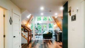 Un interior espacioso con una escalera, un sofá verde y una zona de comedor.