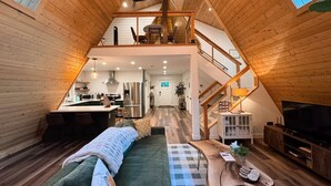 Un dormitorio estilo loft con una cama, un televisor y una escalera que lleva a un nivel superior.