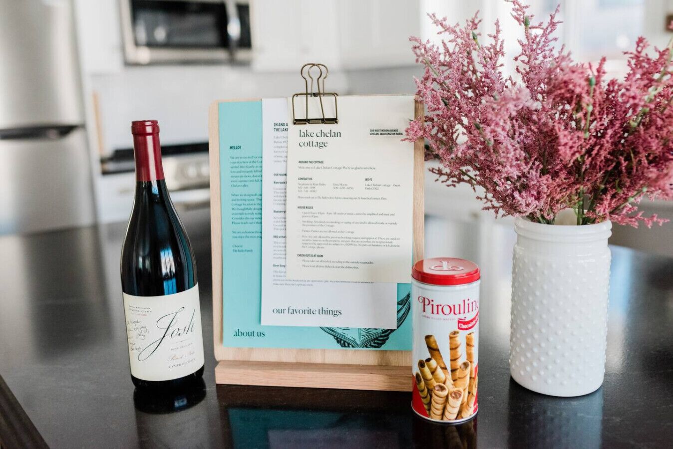 A wine bottle, a menu, and a can of Pirojkin on a kitchen counter.