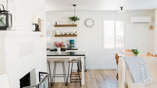 Uma sala de estar moderna com lareira, uma área de jantar com cozinha ao fundo e um espaço de estar acolhedor.