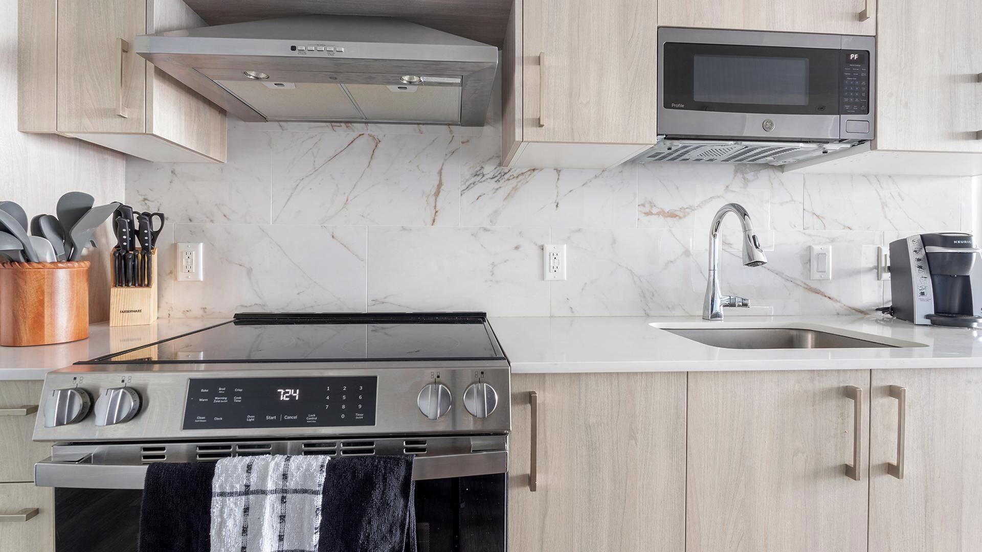 A modern kitchen with a stainless steel stove, a microwave, and a coffee maker.