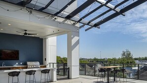 Een terras buiten met een bar, zitplaatsen en uitzicht op de stad.