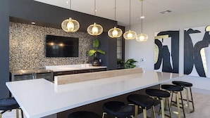 Een moderne keuken met een groot eiland, hanglampen en een flatscreen televisie.