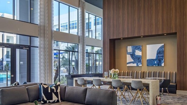 Eine moderne Lobby mit Ecksofa, runden Hocker, einer Essecke und großen Fenstern.
