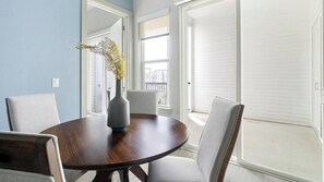 A round dining table with a vase of flowers, two chairs, and a view of a balcony through a door. - Landing | Stunning 2BD, Gym (Houston)