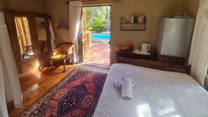 Un dormitori amb un llit, una cadira, una taula petita amb una papereta, una biblioteca i vista a una piscina exterior.