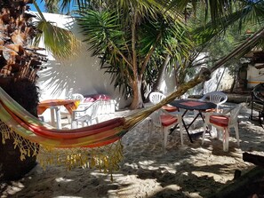 A hammock, outdoor seating, and a table in a sunny, sandy outdoor area. - Room-sunbird Room Double Room With poo (Cape Town)
