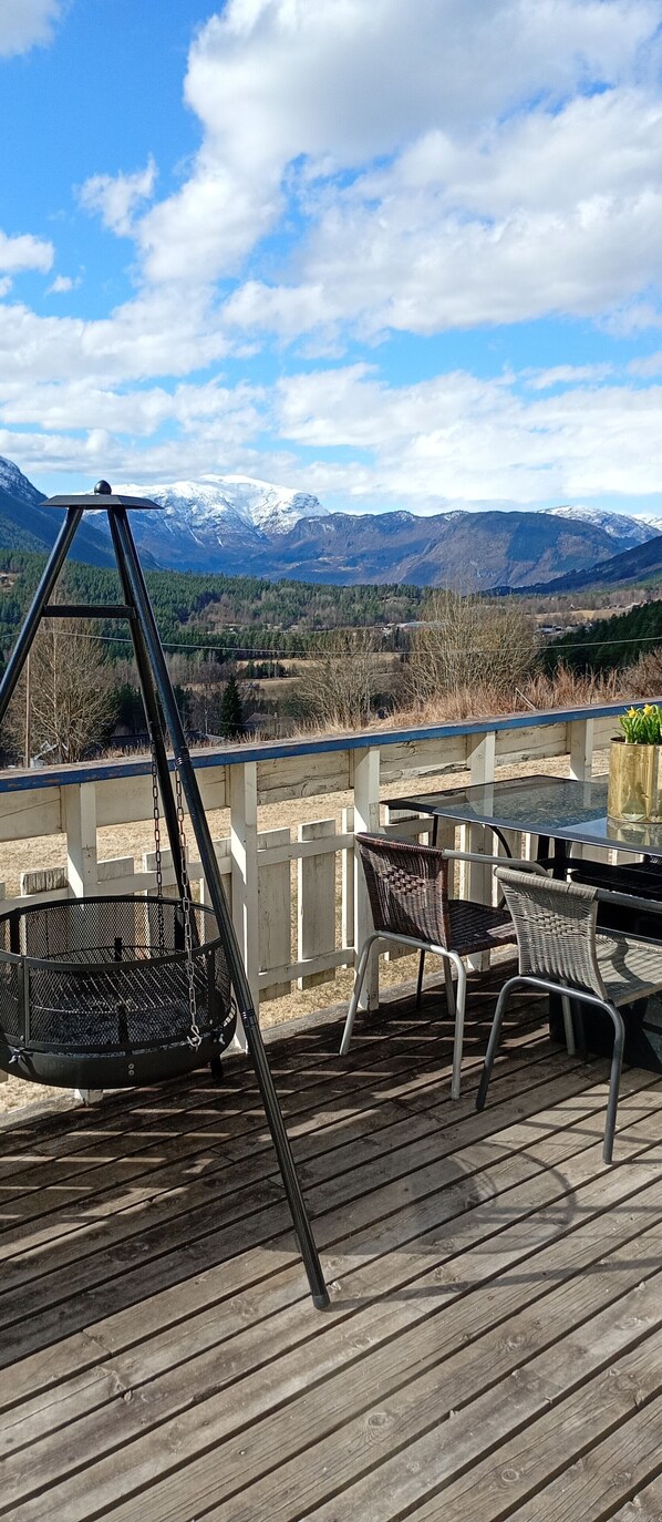 Une terrasse dotée de mobilier d’extérieur, d’une balançoire et offrant une vue sur des montagnes enneigées.