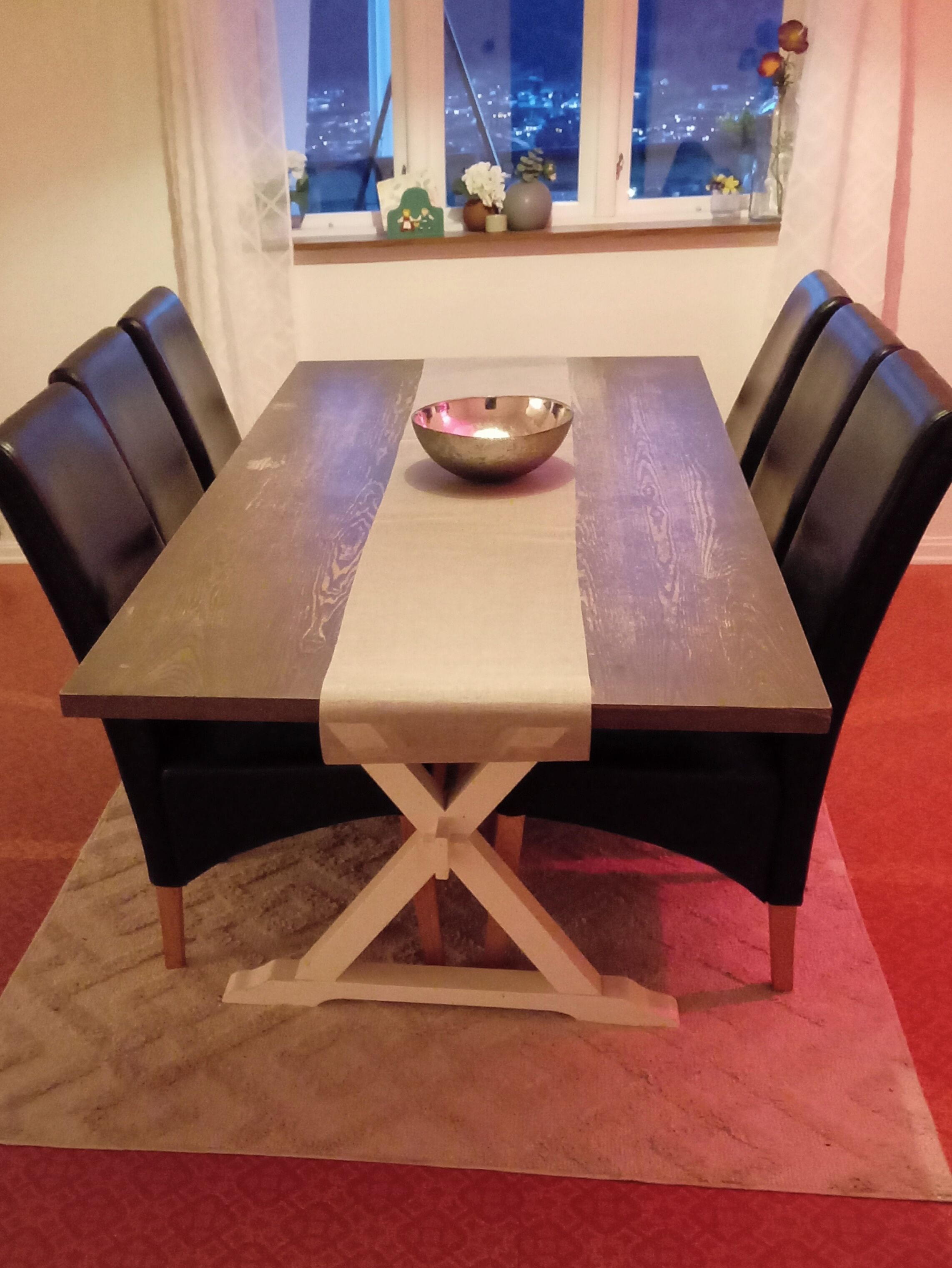 A dining table with a bowl, black chairs, and a window with a city view.