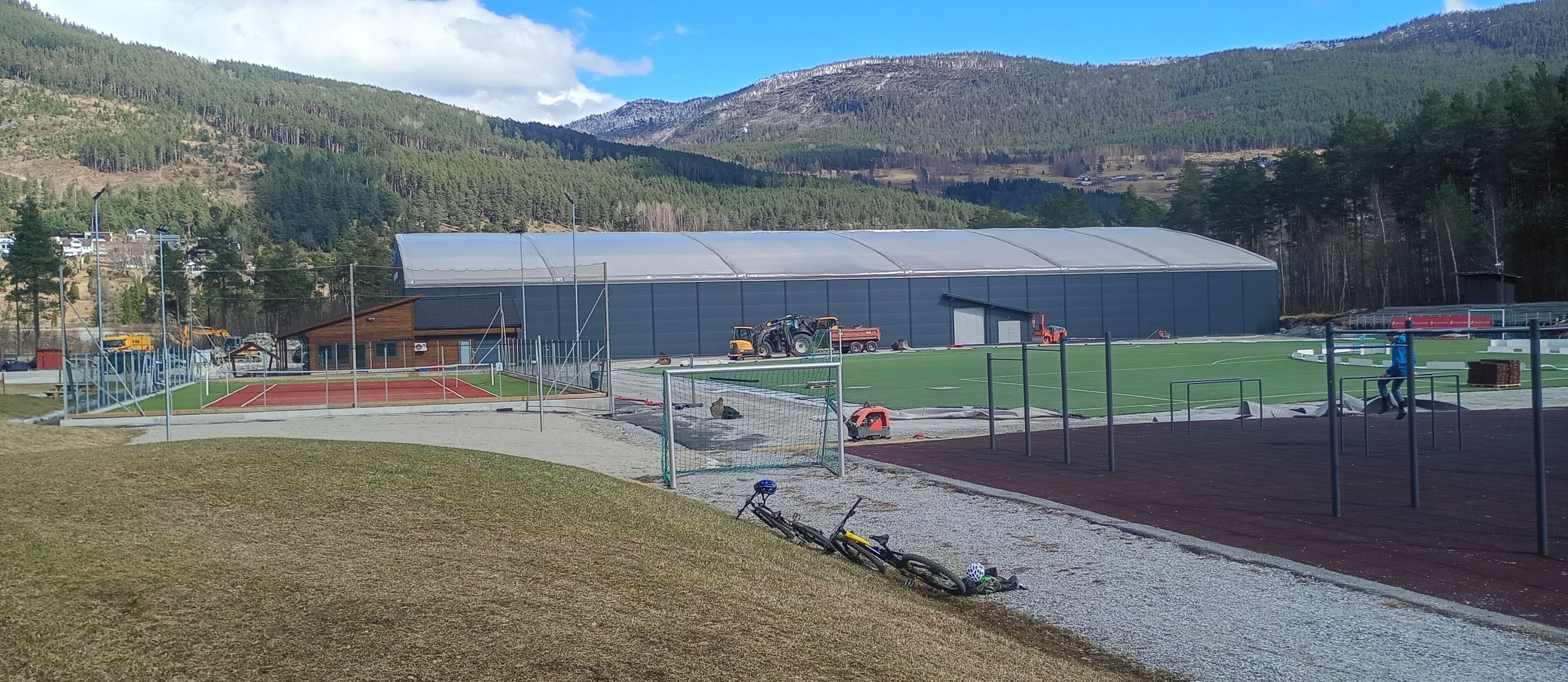 A sports facility with a large building, a running track, and a field.