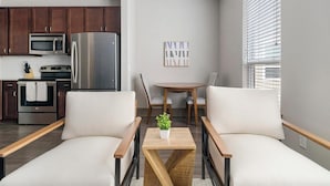 Una cocina moderna con electrodomésticos de acero inoxidable, un comedor con mesa y sillas de madera, y una sala de estar con sofá y mesa de centro.