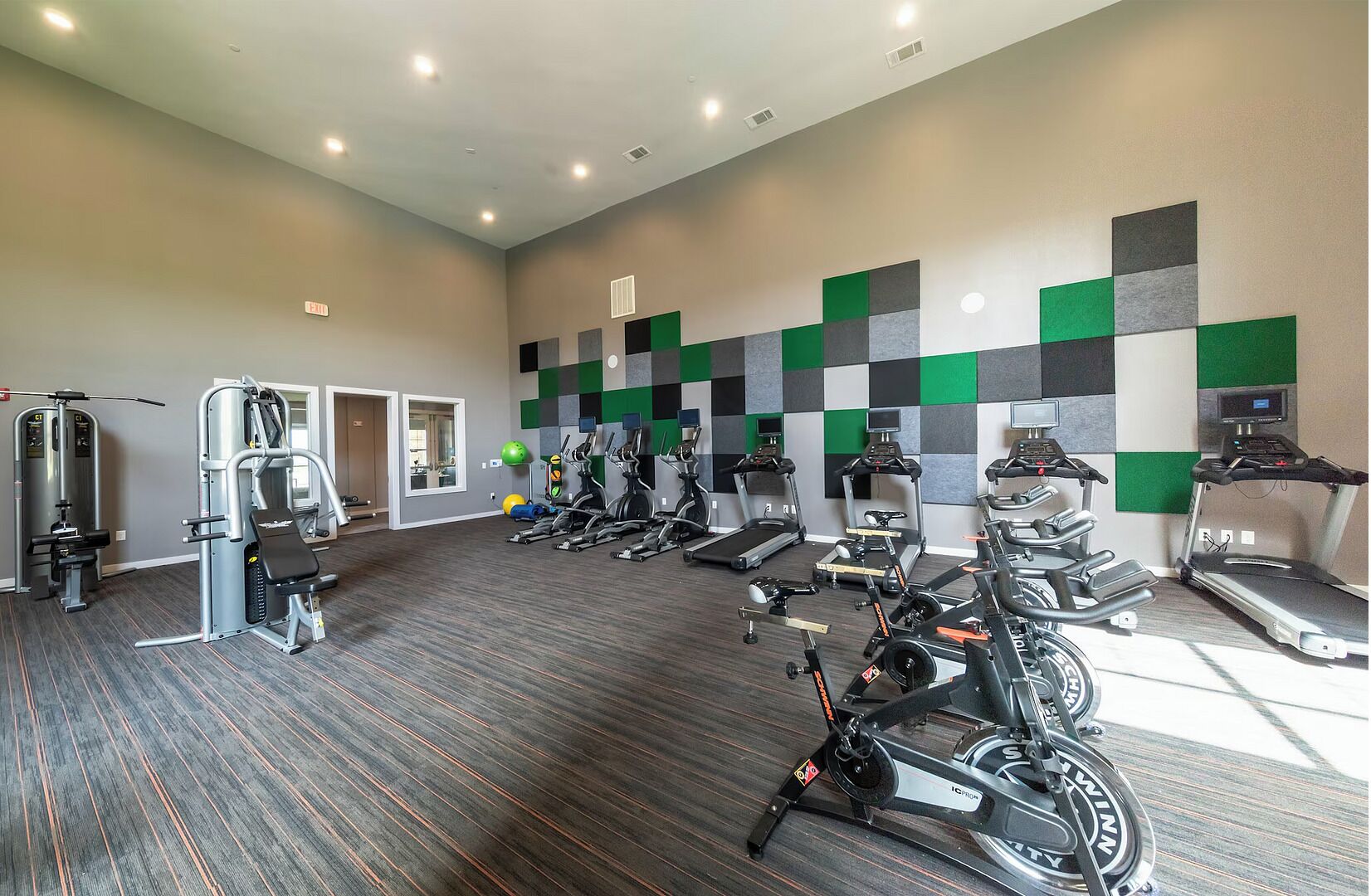 A gym with various exercise equipment, including treadmills, stationary bikes, and weight machines.