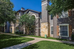 A residential building with a stone facade, multiple windows, and a well-maintained lawn. - Landing | Stylish 2BD in Cityview (Fort Worth)