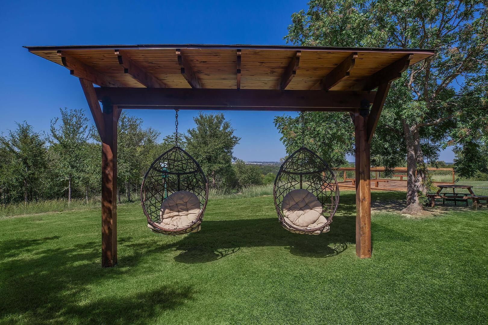Una pérgola de madera con dos asientos tipo columpio.