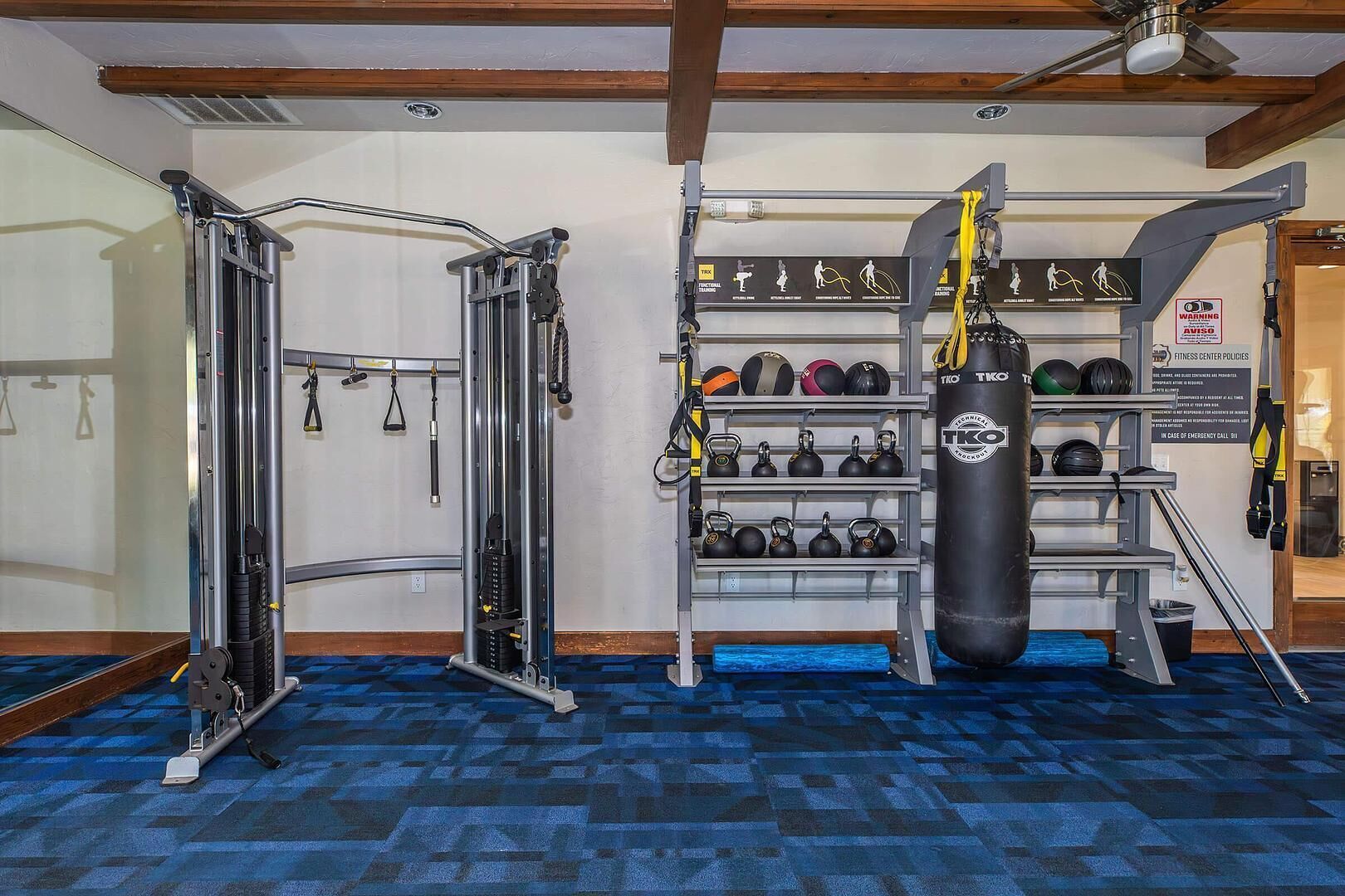 A gym with weightlifting equipment, kettlebells, and a punching bag.