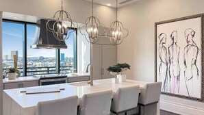 A modern kitchen with a large island, bar stools, pendant lighting, and a city view. - Landing | Stylish Studio, Gym, Clubhouse (Houston)