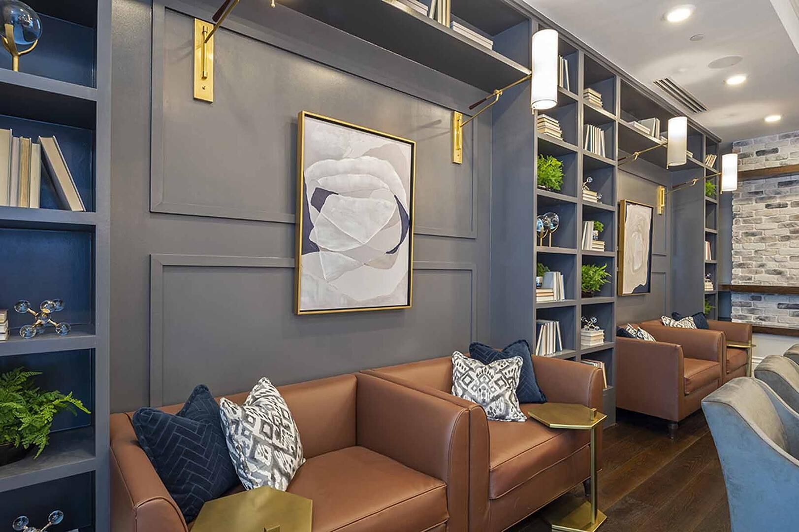 A modern lounge area with leather sofas, bookshelves, and a large abstract painting.