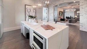 A modern kitchen with a large island, built-in oven, and pendant lighting. - Landing | Stylish Studio, Gym, Clubhouse (Houston)