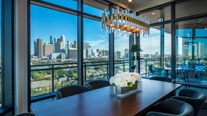 A modern conference room with a city skyline view, a chandelier, and a vase of flowers on the table. - Landing | Stylish Studio, Gym, Clubhouse (Houston)