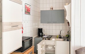 Una cocina compacta equipada con microondas, cafetera y refrigerador pequeño.