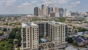 A multi-story hotel with a rooftop pool, surrounded by a cityscape. - Landing | Stylish Studio, Gym, Yoga Studio (Houston)
