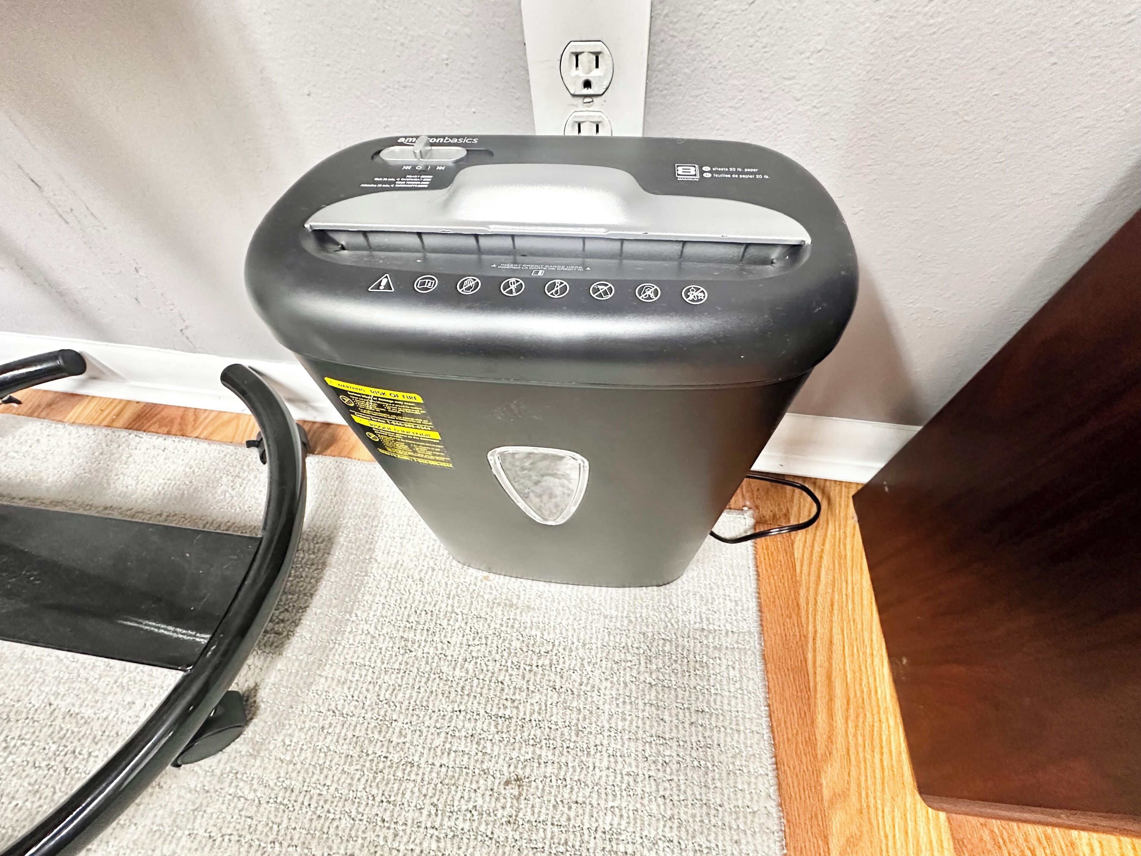 A gray portable heater with a power cord, a warning label, and a protective shield on a carpeted floor.