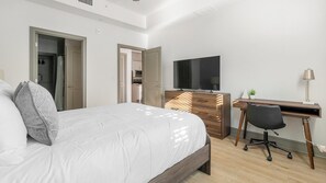 Ein Schlafzimmer mit einem Bett, einem Schreibtisch, einem Stuhl, einem Fernseher und einer Kommode.