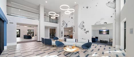 A spacious living area with a high ceiling, modern furniture, and a large flat-screen TV.