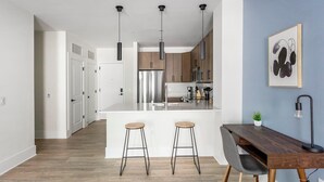 Cocina moderna con isla central, electrodomésticos de acero inoxidable e iluminación colgante.