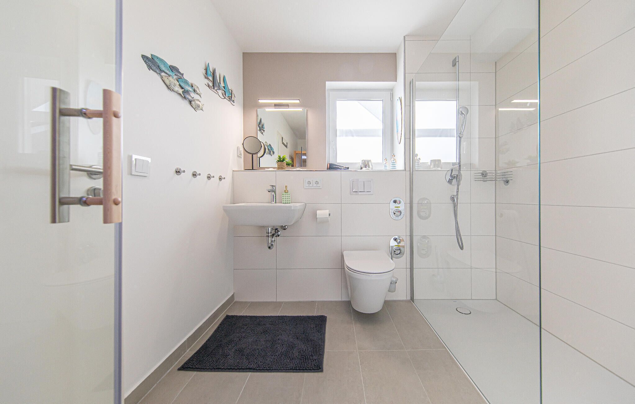 A modern bathroom with a glass shower enclosure, a white sink, a toilet, and decorative wall art.