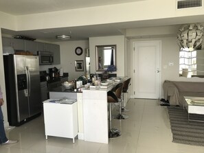 A modern kitchen with a refrigerator, microwave, and dining area. - Bright 2-bedroom apartment with AC in peaceful Miami neighborhood (Miami)