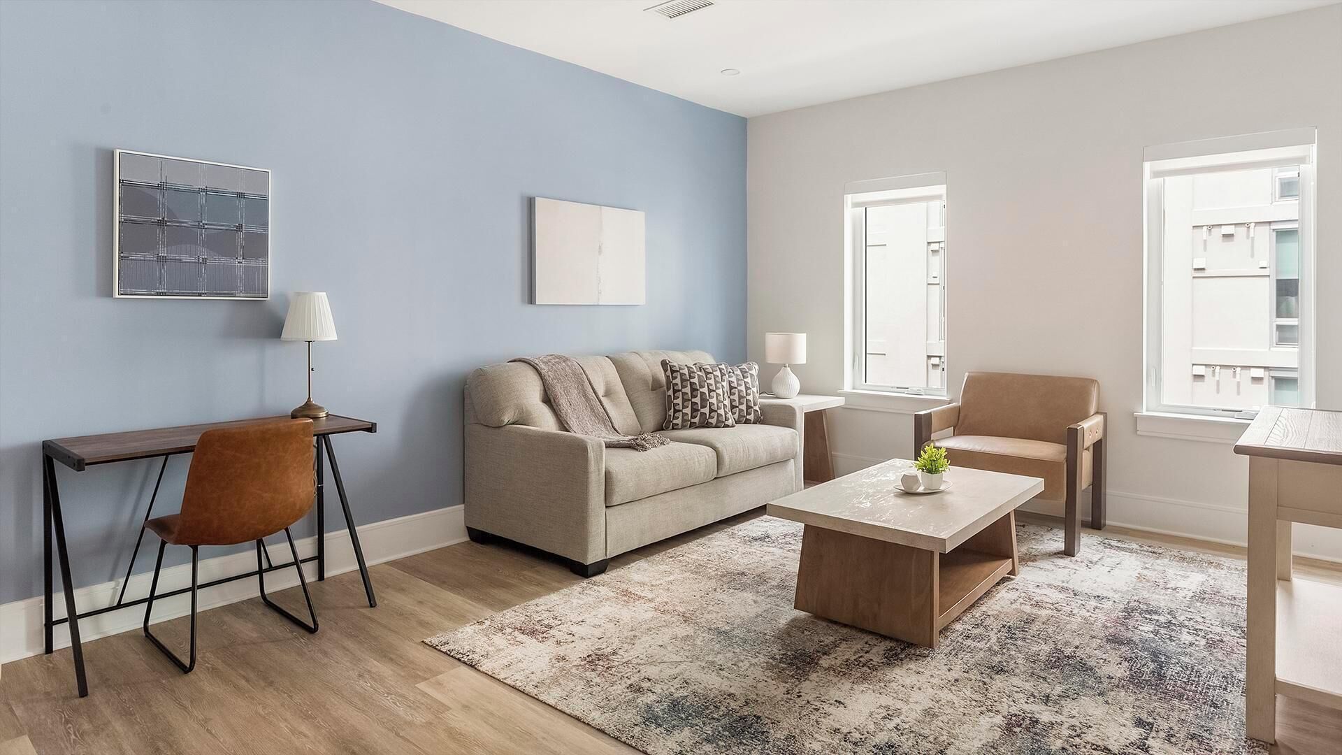 Un salon moderne comprenant un canapé, une table basse et un bureau avec une chaise.