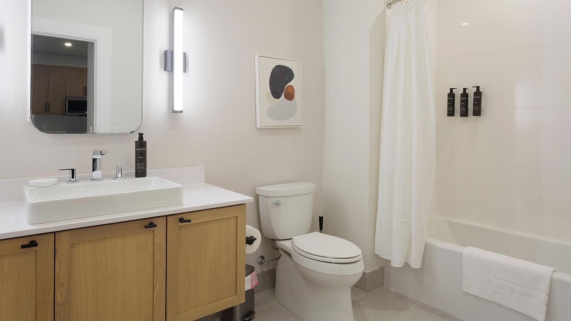 Een moderne badkamer met een wit wastafelmeubel, toilet en bad.