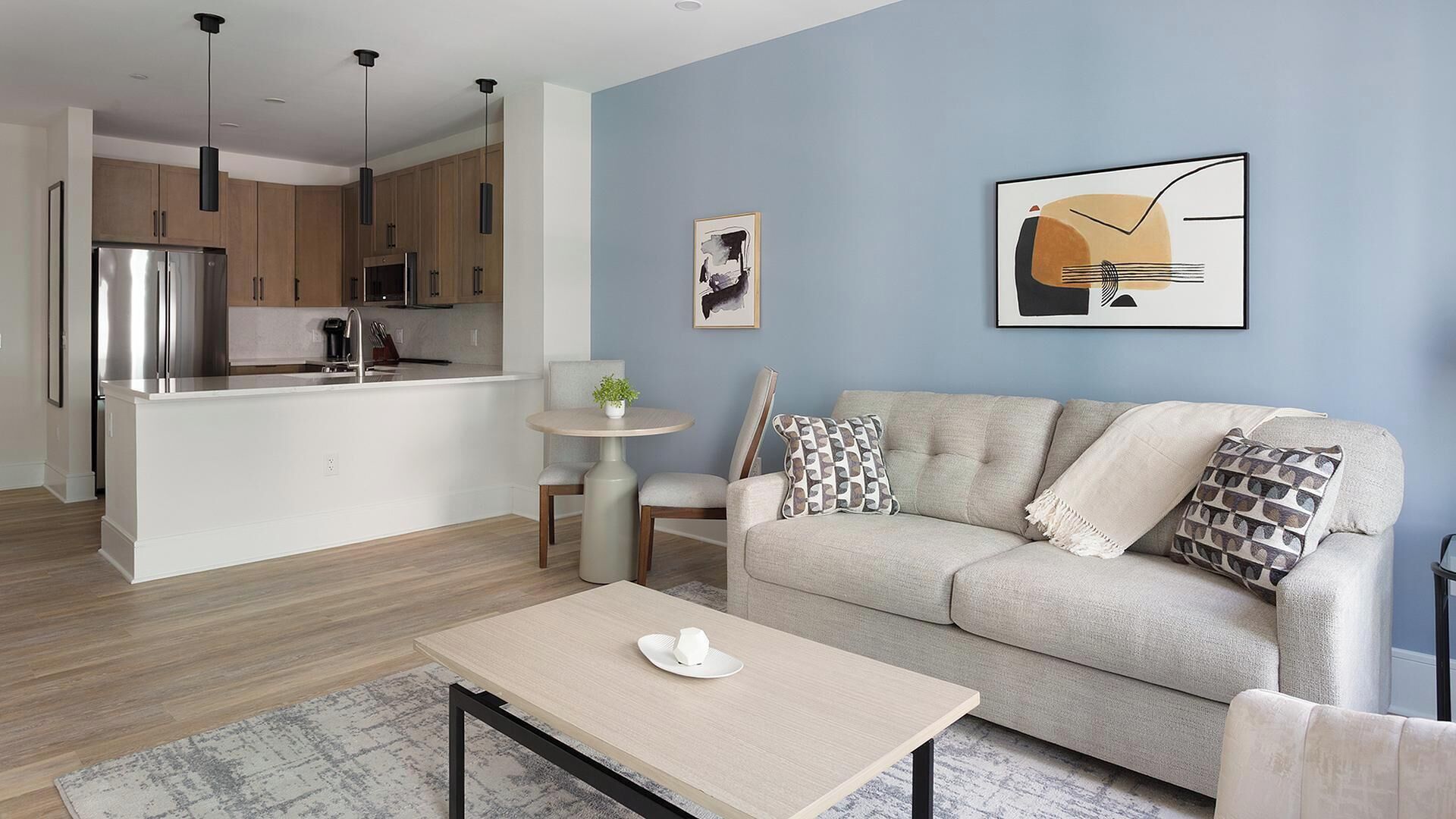 Un salon moderne comprenant un canapé, une table basse et un coin repas avec une petite table et des chaises.