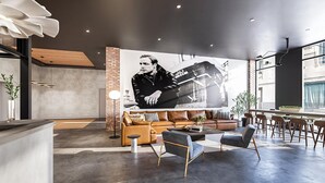 A modern interior with a large mural, leather sofas, and a bar area. - Landing | Chic 1BD, Pool (Philadelphia)