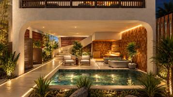 Un área de piscina interior moderna con una escalera, asientos y una pared de madera.