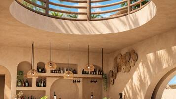 A circular bar area with a wooden railing, pendant lights, and shelves with bottles.