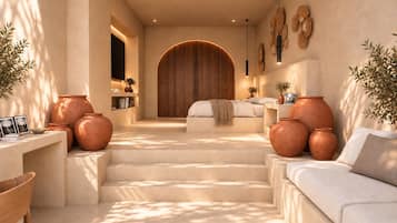 Un interior moderno con una escalera que conduce a un dormitorio, con macetas de terracota, un sofá y una puerta de madera.