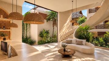 A modern interior with a curved sofa, a round wooden coffee table, and a spiral staircase.