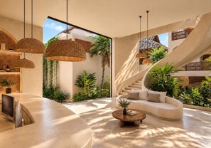 Un intérieur moderne avec un canapé aux lignes courbes, une table basse ronde en bois et un escalier en colimaçon.