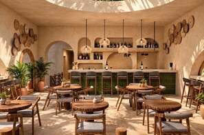 Un restaurante con mesas y sillas de madera redondas, una zona de bar con estanterías llenas de botellas y decoración en las paredes.