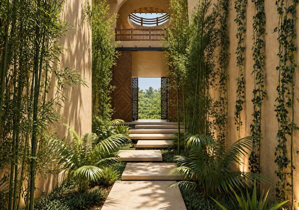 Un sendero conduce a una entrada con puerta, flanqueado por abundante follaje.