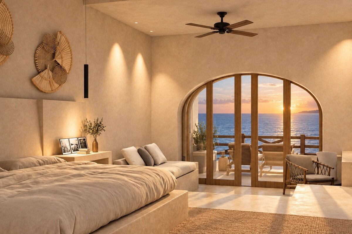 Un dormitorio con una cama grande, un rincón de estar con vista al mar y un ventilador de techo.