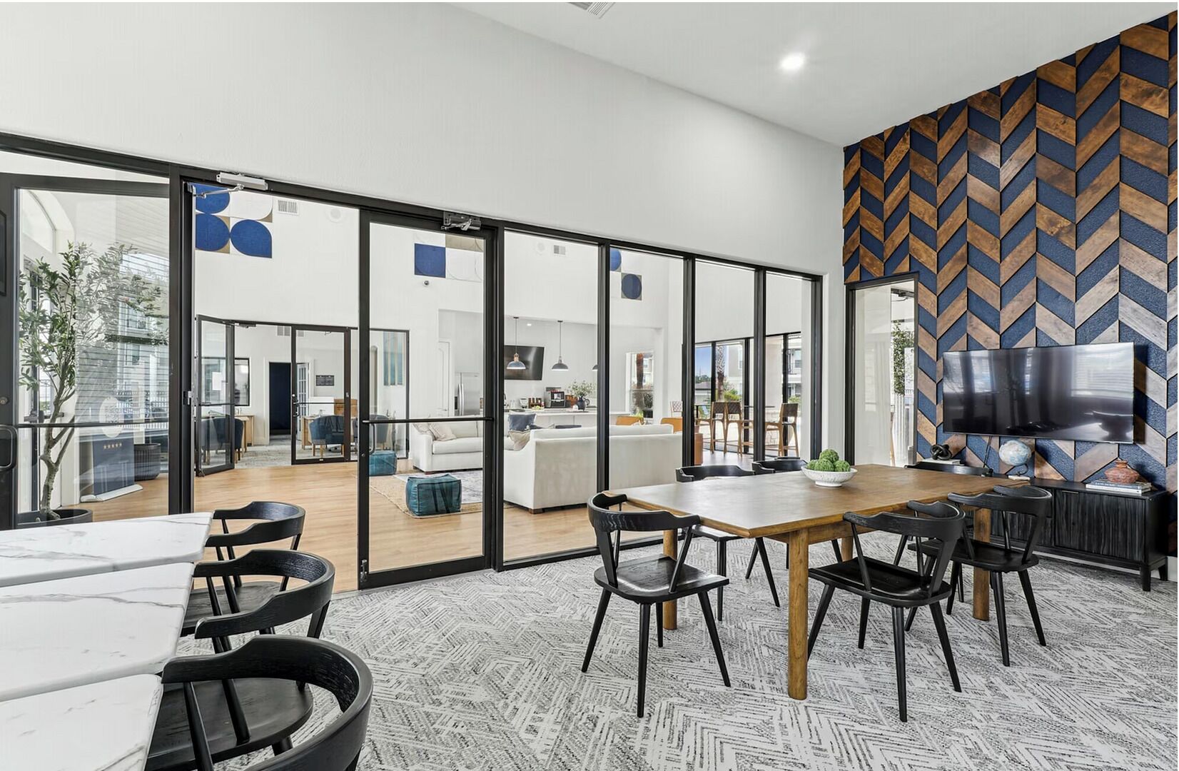 Un intérieur moderne comprenant un coin repas, de grandes fenêtres et un mur orné d’un motif en chevrons.