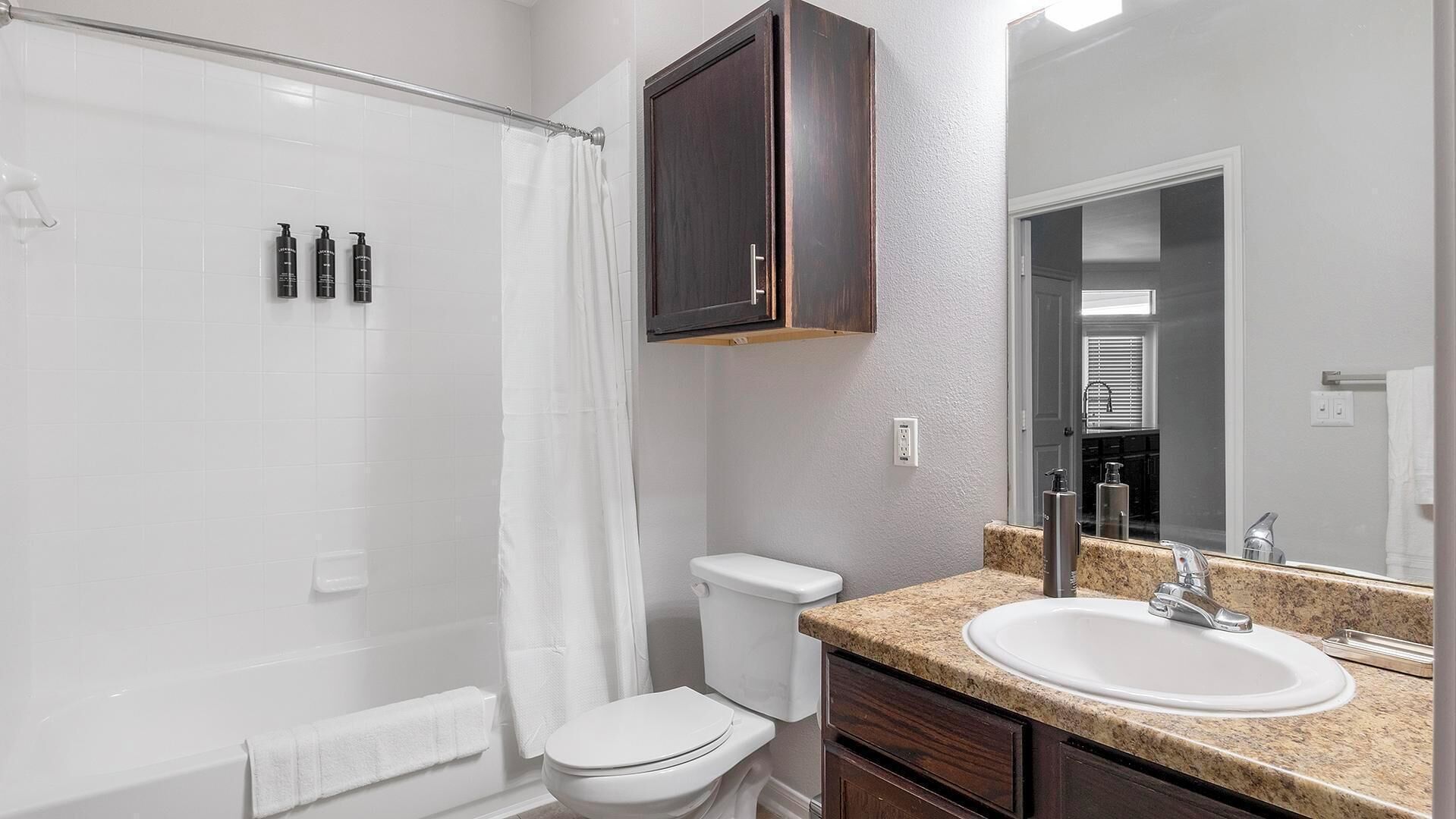 Une salle de bain équipée d’une douche, de toilettes, d’un lavabo et d’un miroir.