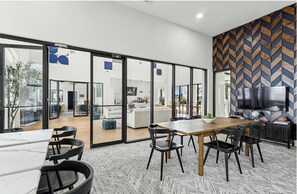 A modern interior with a dining area, large windows, and a herringbone-patterned wall. - Landing | Amazing 2BD, Clubhouse, Gym (Houston)